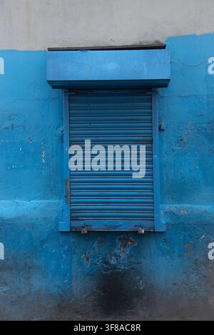 Locked Blue Roller Shutter Set into Weathered Two-Tone Urban Wall Stock Photo