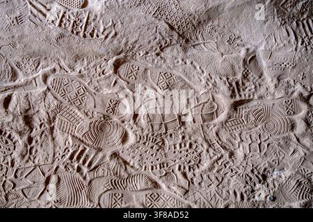 Close-up of overlapping footwear tread impressions pressed into a sandy ground surface, showing variety of distinct sole patterns from multiple shoes Stock Photo