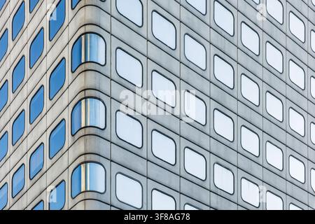 Geometric facade with repeating rounded windows and blue reflections in Hong Kong city, China. Abstract architecture background, symmetry, repetition Stock Photo