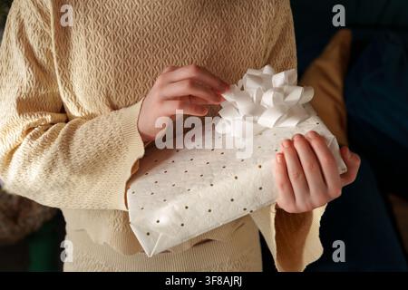 Close up of teen girl touching bow on Christmas gift at home Stock Photo