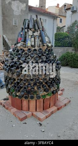 Baska, Croatia - June 11, 2020. Art installation of a giant bottle like a big demijohn made from wine bottles, cement and bricks on a street. Stock Photo