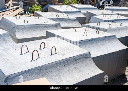 Large reinforced concrete foundation blocks lying on the ground ready for installation. Perfect stock photo for heavy construction, urban development, Stock Photo