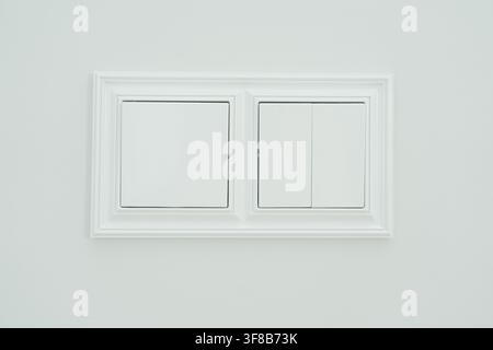 Modern two-rocker electrical light switch installed on a clean interior wall. Perfect stock photo for home energy saving, lighting controls, modern Stock Photo