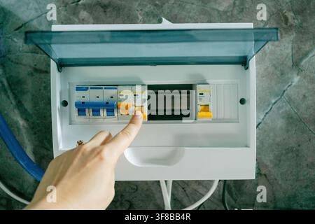 Close-up view of a person operating a breaker switch in an electrical control panel. Perfect stock image for electrician work, power grid management Stock Photo