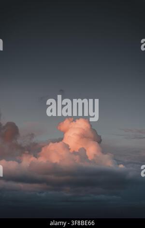 View of a large, pink-lit cumulus cloud formation against a dark, moody evening sky over Vormsi, Laane County, Estonia. Stock Photo