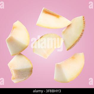 Pieces of melon flying in air on pink background Stock Photo