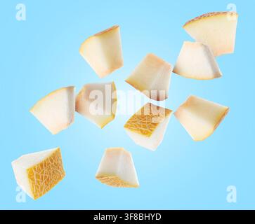 Pieces of melon flying in air on light blue background Stock Photo