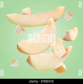 Sweet melon pieces flying in air on pastel green background Stock Photo