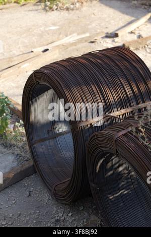 Two large rolls of rusty steel rebar, bound together with metal strapping, stand ready for use as essential building materials in an industrial settin Stock Photo