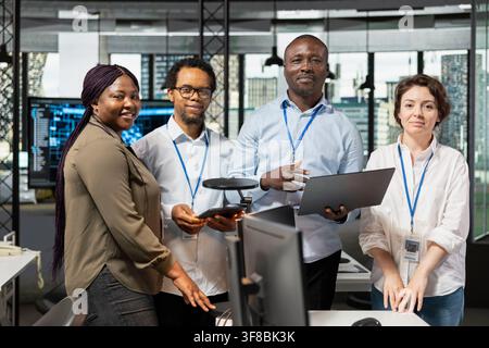 Portrait of cheerful team members in office working with software development programming languages. Jolly teamworking colleagues using notebook in startup to do code testing and quality assurance Stock Photo