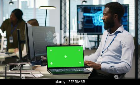 Startup office programmer using green screen laptop, developing artificial intelligence models for business analytics. IT expert using mockup notebook, running simulations for AI forecasting, camera A Stock Photo