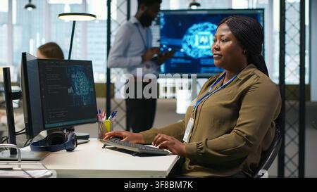 Female admin using AI neural networks tech on computer to optimize performance and forecast issues. Woman in office training artificial intelligence deep learning models using PC, camera A Stock Photo