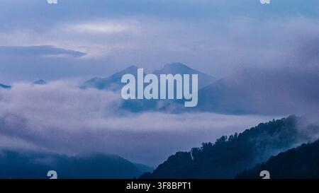Aerial view of the misty mountains surrounding Lake Vidraru with dense forest slopes and low hanging clouds in the Fagaras Mountains, Arefu, Arges, Ro Stock Photo