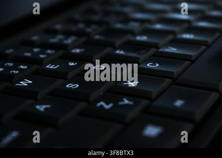 Extreme close-up of backlit black laptop keyboard keys at an angle Stock Photo