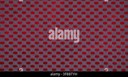 Close-up of red perforated mesh pattern with dark holes, suitable for abstract background, industrial texture Stock Photo