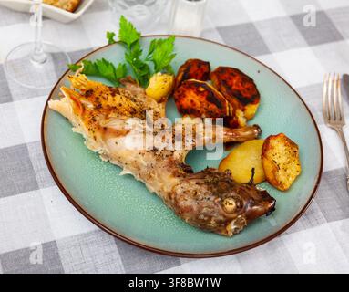 Baked potatoes with roasted rabbit and fresh greens Stock Photo