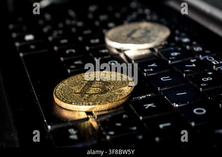 Gold bitcoin coins resting on a laptop keyboard Stock Photo