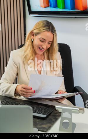 Businesswoman laughing while analyzing data and statistics in office Stock Photo