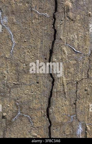 Close-up of long, wide and deep vertical crack on damaged beige and tan colored concrete surface, Quebec, Canada Stock Photo