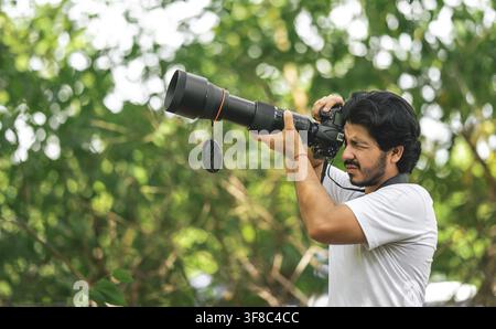 Wildlife photographer with telephoto camera in natural environment. Nature photographer using professional camera with telephoto lens Stock Photo