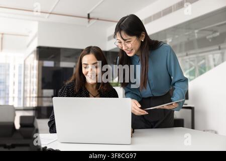 Two smiling businesswomen collaborating on laptop in office Stock Photo