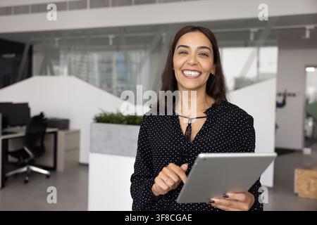 Portrait of Arabian businesslady, marketing specialist or project manager posing in office with tablet, looking at camera, exuding professionalism and Stock Photo
