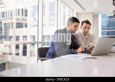 Two male corporate executives coworkers collaborating on project on laptop Stock Photo