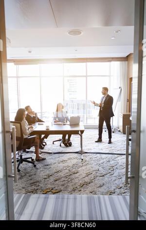 Businessman presenting strategy to colleagues during meeting in conference room. Stock Photo