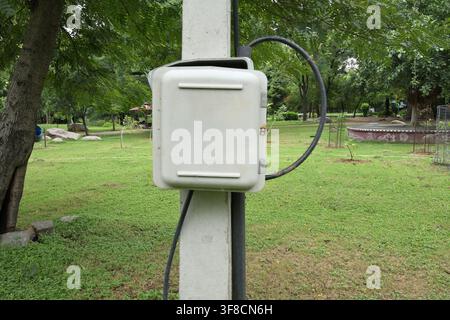 Outdoor electrical junction box mounted on utility pole in public park landscapes Stock Photo