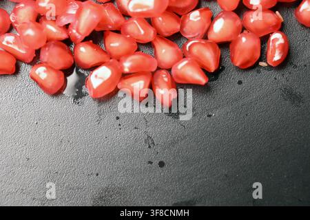 Glossy Ruby Pomegranate Seeds on Black Stone Backgrounds Stock Photo