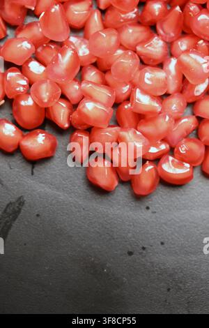 Glossy Ruby Pomegranate Seeds on Black Stone Backgrounds Stock Photo