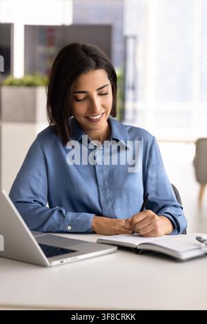 Businesswoman writing notes working at office desk Stock Photo