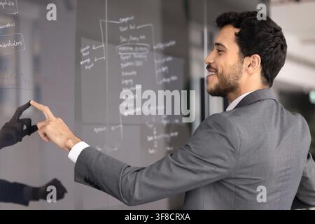 Businessman pointing on written notes at glass board Stock Photo
