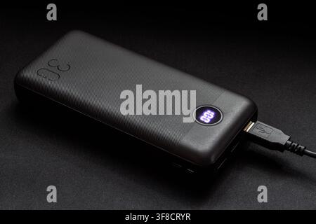 A modern power bank on a dark background. Battery for charging devices. Stock Photo