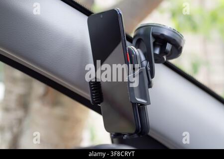 Smartphone in a special holder on the windshield of the car. Phone holder in the car. Stock Photo