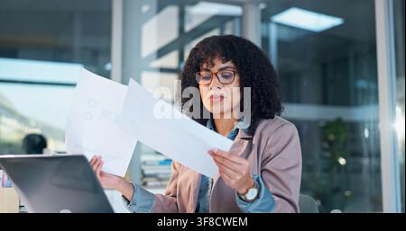 Woman, laptop and finance with documents in office for performance review, results or statistics. Female person, analyst or checking paperwork with Stock Photo