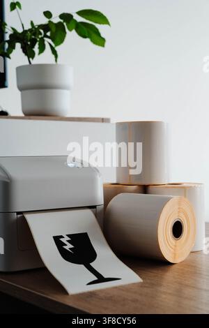 Packaging printer with rolls of labels and fragile shipping symbol for small business fulfillment. Packaging automation streamlines order processing Stock Photo