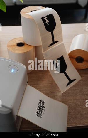 Label printer, paper rolls and fragile shipping labels for small business order fulfillment. Packaging automation streamlines ecommerce operations and Stock Photo