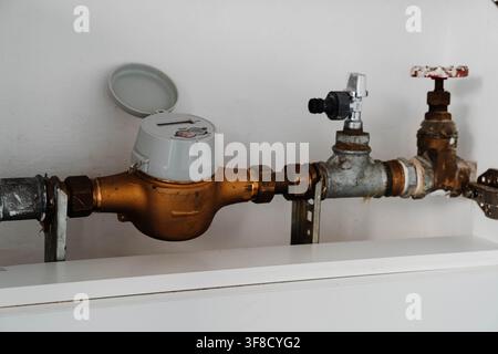 Water meter and plumbing valve for household water usage inspection. Regular meter inspection supports accurate readings, leak detection and utility Stock Photo