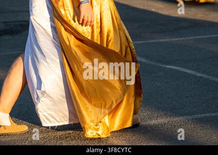 Golden satin cloak and white dress details of a roman reenactor in motion Stock Photo