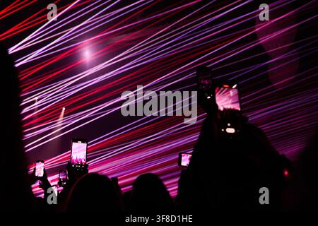 Ryazan, Russia, 28.09.2025 Crowd of people holding up smartphones to record bright red and purple stage laser lights during a concert party. Live musi Stock Photo