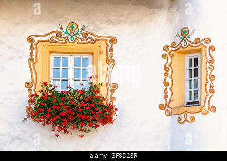 Traditional alp windows with ornate painted frames on a white textured wall Stock Photo