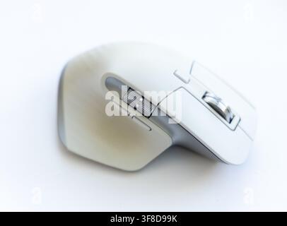 A modern wireless computer mouse sits on a white surface Stock Photo