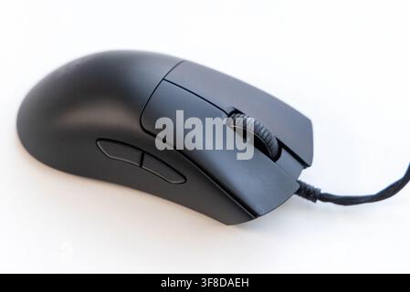 A modern black computer mouse sits on a white surface Stock Photo
