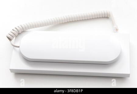 A modern white intercom handset lies on a flat surface Stock Photo
