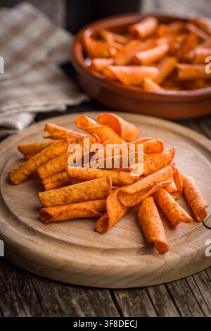 Spicy rolled tortilla chips seasoned with paprika and chili, piled beside a clear glass bowl on a white background. Crispy, crunchy snack ideal for pa Stock Photo