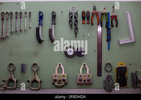 Moscow, Russia, 10.04.2020 Collection of various auto service tools hanging on a green wooden wall in a workshop. Automotive repair equipment for gara Stock Photo