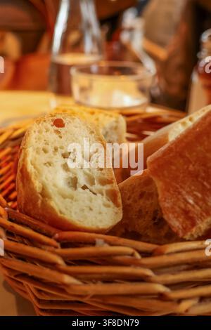 Basket filled with fresh sliced baguette bread on a table, ready to be enjoyed as part of a meal in a cafe setting Stock Photo
