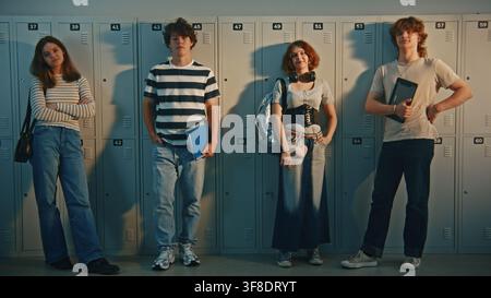 Portrait of Modern Gen Z High School Students Standing Together in Locker Room Corridor. Technology in Schools, Diverse Individual Styles, Everyday Student Routines in Modern Educational Settings. Stock Photo