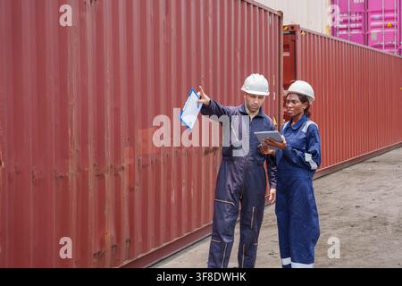 Warehouse workers collaborating on logistics plans while reviewing documents in shipping yard. Ideal for concepts related to logistics, business teamw Stock Photo